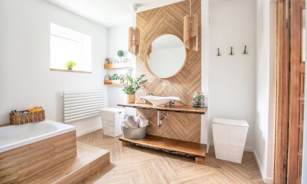 White sink on wood counter with a round mirror hanging above it. Bathroom interior.